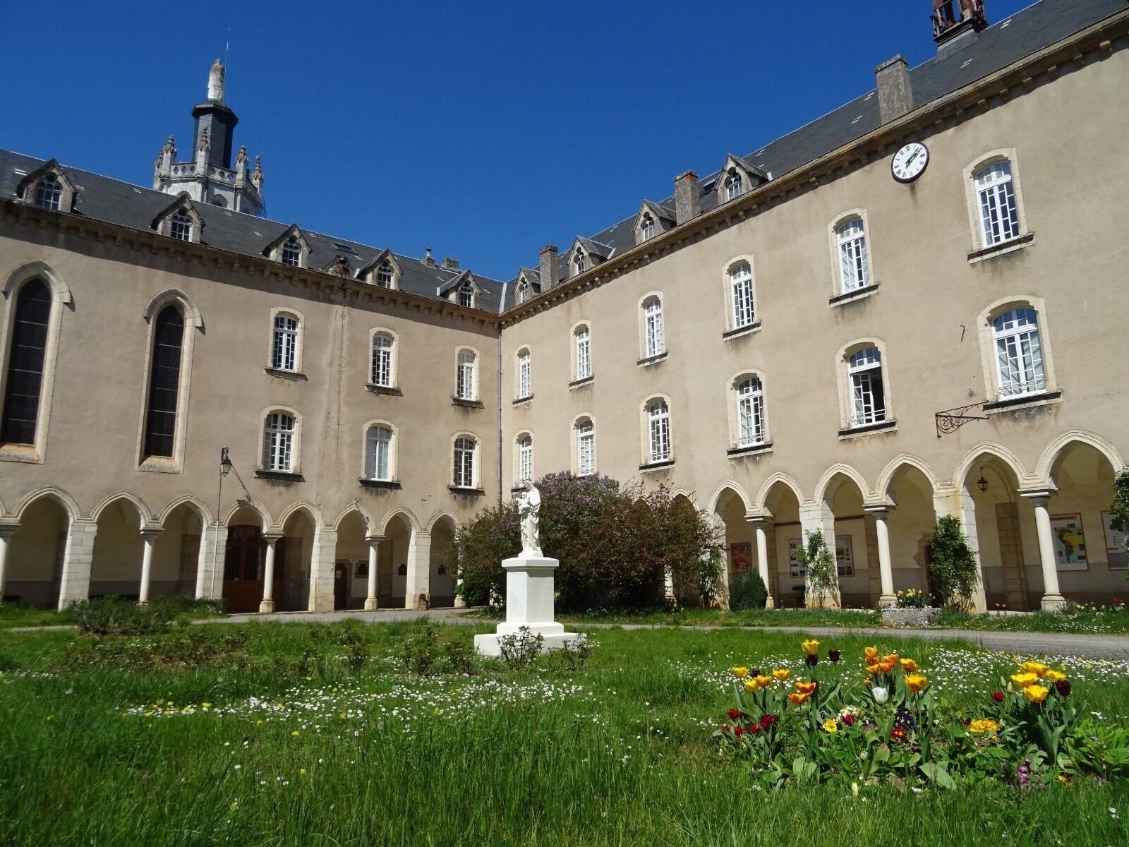 A courtyard with a central fountain, surrounded by a building with multiple windows and arches.