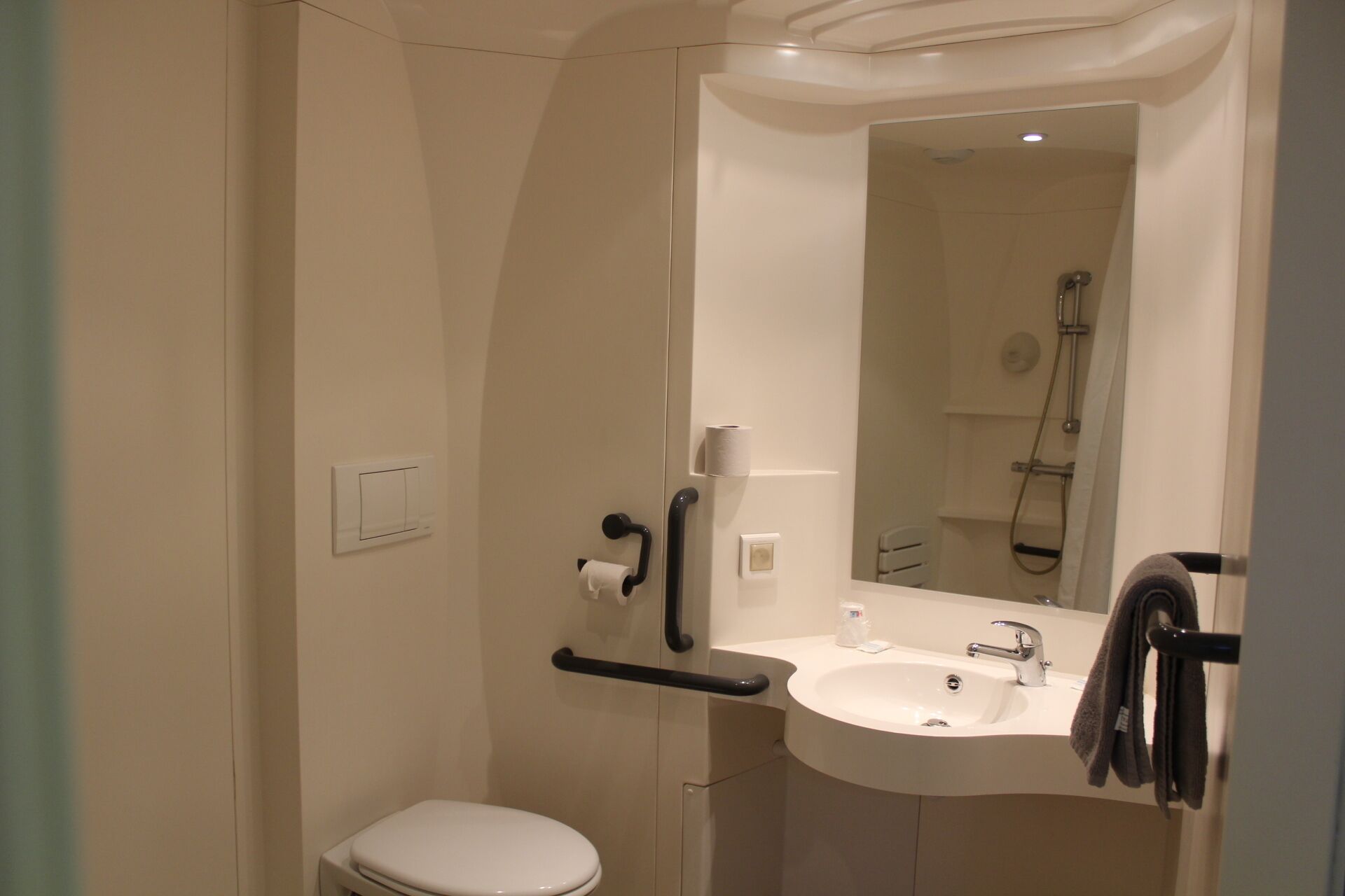 Un baño pequeño y moderno con inodoro, lavamanos y ducha.