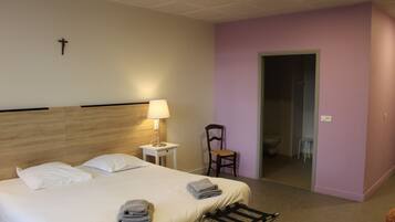Une chambre d’hôtel avec un lit, une chaise, une table de chevet et une lampe.