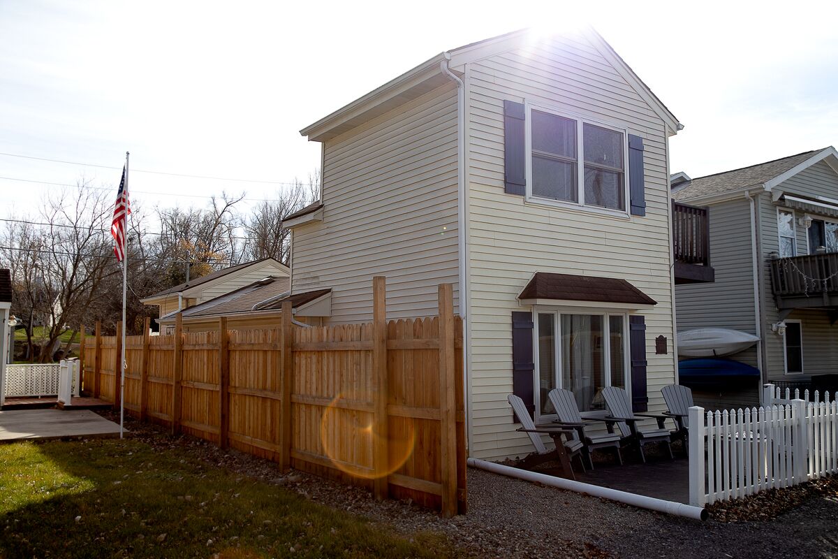 A two-story house with a patio area featuring outdoor furniture.