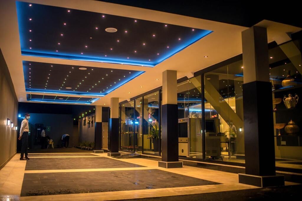 A modern hotel lobby with a spacious layout, glass doors, and a ceiling with embedded lighting.