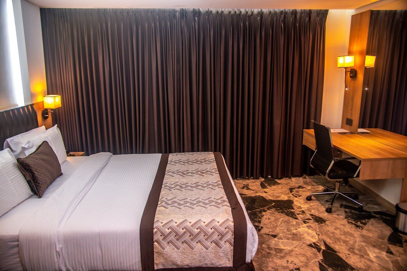 Een hotelkamer met een bed, een bureau en een stoel.