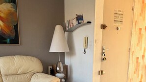 Une chambre d’hôtel avec un lit, un canapé, une lampe, une porte sur laquelle sont affichées les règles de l’hôtel, et un tableau au mur.