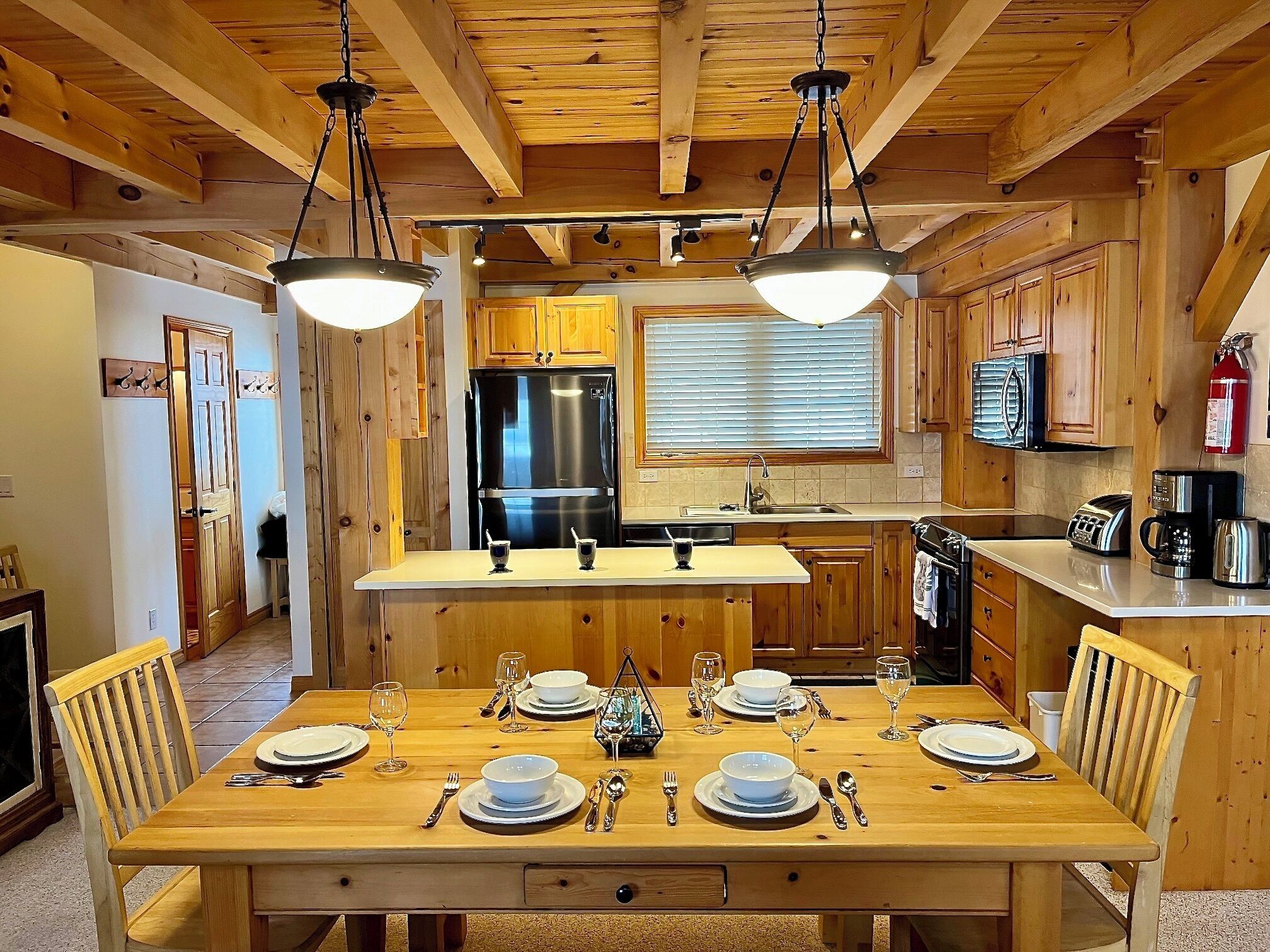 Un intérieur en bois comprenant une table à manger pour six personnes, des appareils de cuisine et des meubles de rangement en bois.