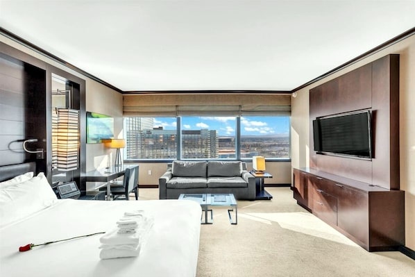 A modern hotel room with a large bed, a sofa, a TV, and a city view. - Premium Studio Suite at Vdara (Las Vegas)