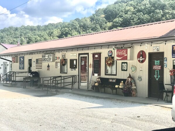 A building with a red roof, signs for 'Bobby and Betty Grocery', 'Ice', and 'Pepsi'. There are outdoor seating areas and a gravel parking lot. - Old Rustic Country store near Pine mtn. / Kingdom Come Park & Bad Branch Falls  (Partridge)