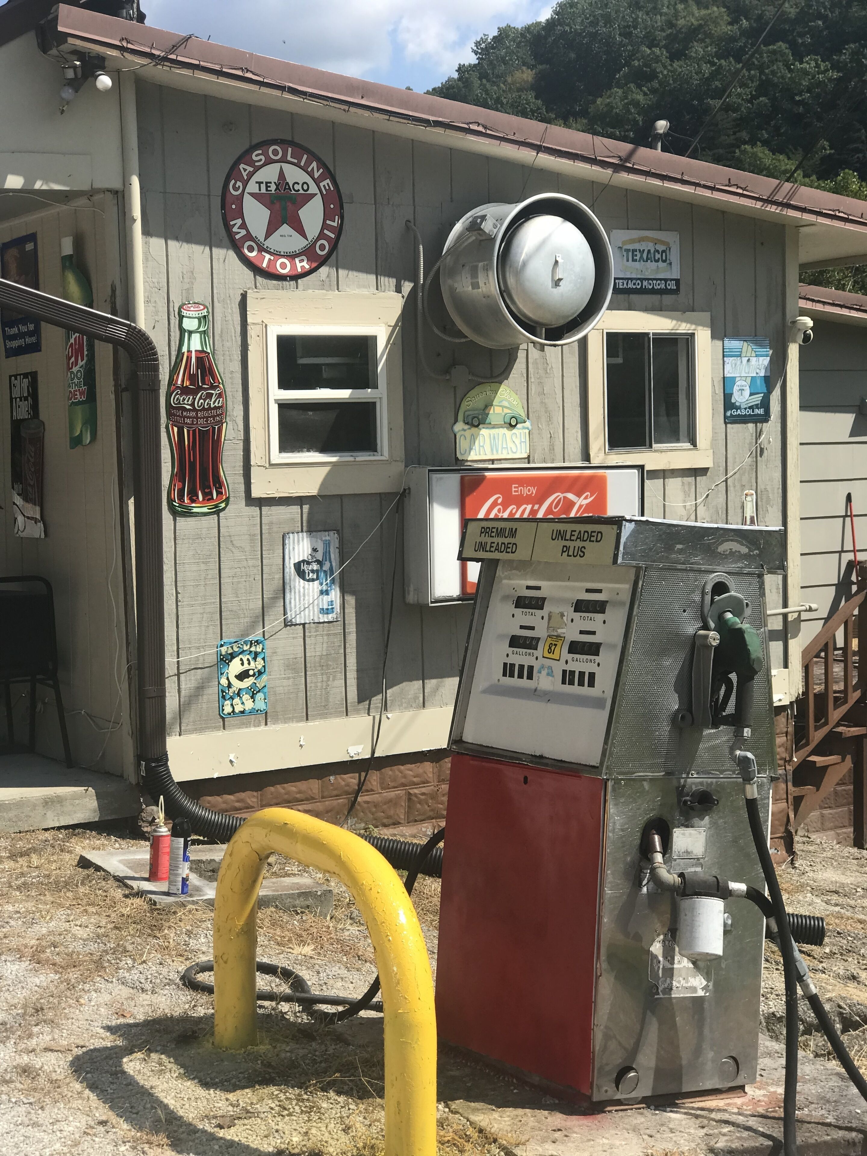 A vintage gas station with a Coca-Cola sign, a Texaco logo, and a car wash sign.