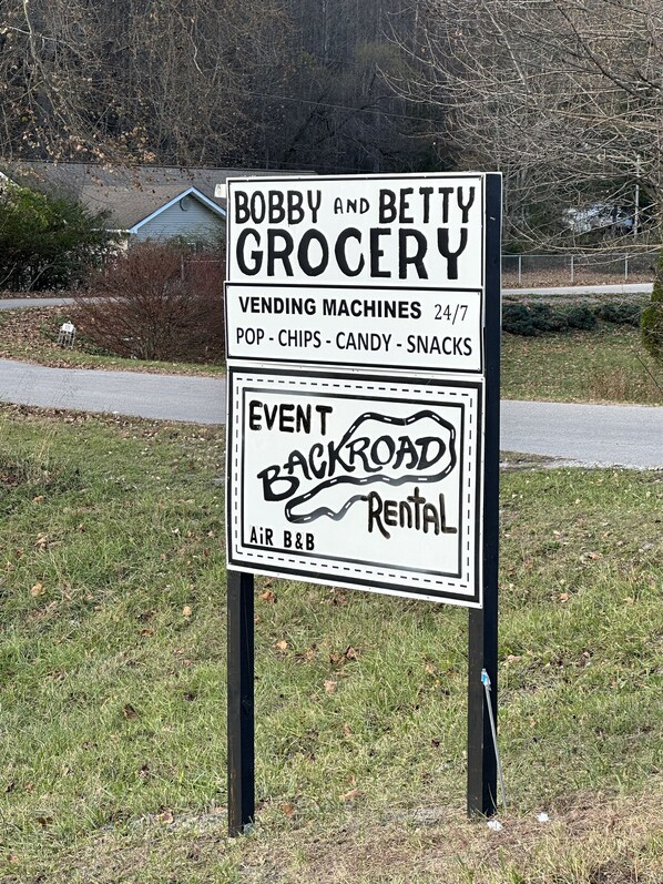 A sign for Bobby and Betty Grocery, a 24/7 vending machine store, and an event backroad rental.