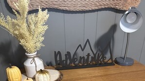 Un aparador de madera con cajones de mimbre y un florero con plantas secas encima.