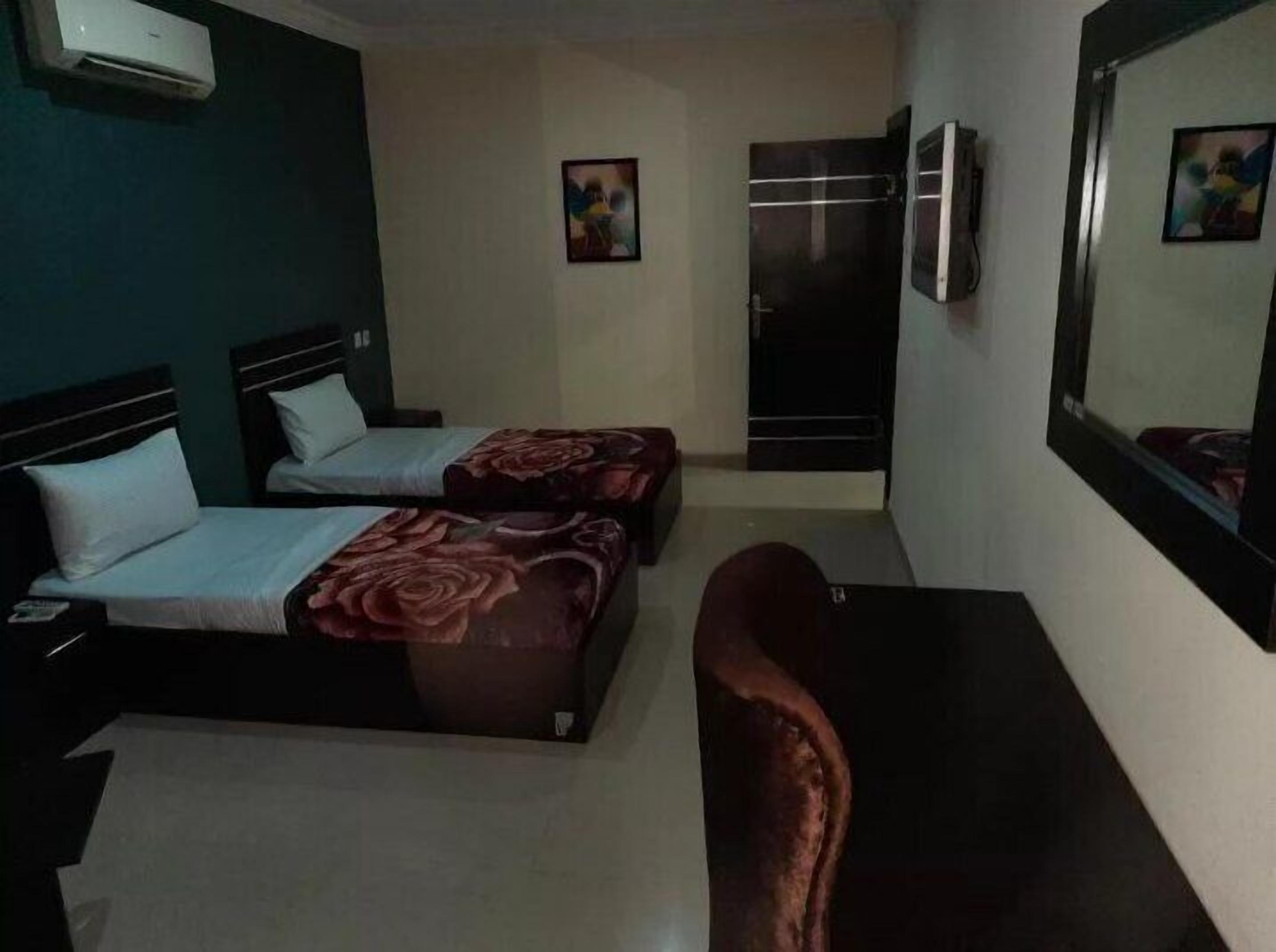 Una habitación de hotel con dos camas, un escritorio, una silla y un armario.