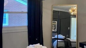 Ein Hotelzimmer mit einem großen Bett, einer modernen Kronleuchter, einem großen Spiegel und Blick ins Freie.