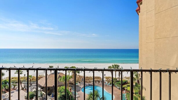 Een balkon met uitzicht op een strand en een zwembad.