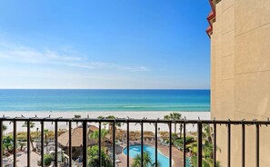 Een balkon met uitzicht op een strand en een zwembad.