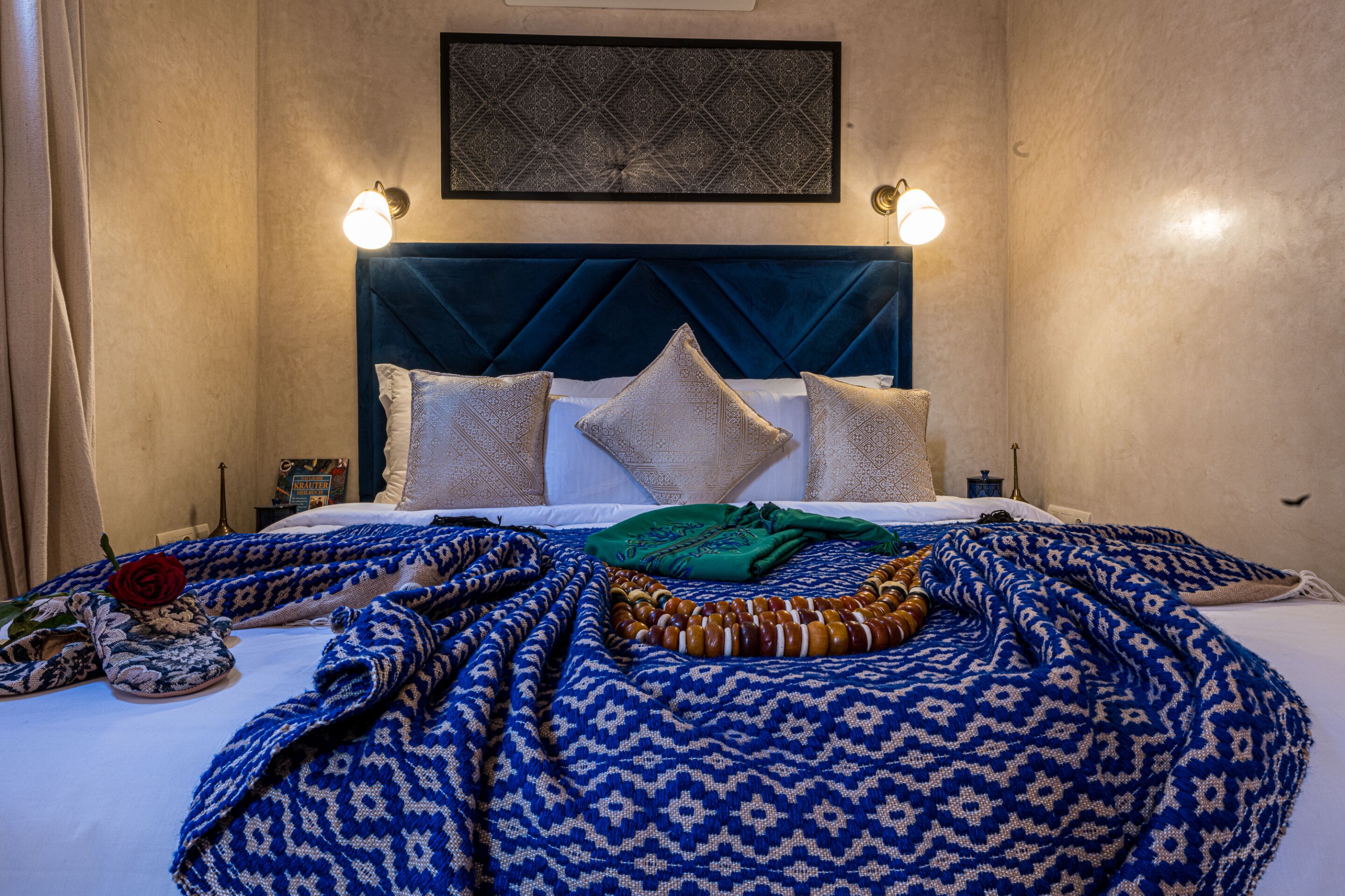 Een keurig opgemaakt bed met een beddengoed met patroon, kussens en een decoratief object ernaast.