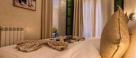 A neatly made bed with a patterned blanket, a large decorative pillow, and a painting on the wall.