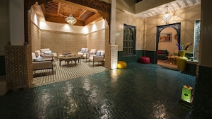 A spacious lobby with a checkered floor, a seating area with sofas and a coffee table, and a decorative ceiling. - Riad Atrium (Marrakech)