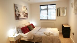 A bedroom with a bed, nightstand, dresser, and artwork on the wall. - Home In Birmingham New Street (Birmingham)