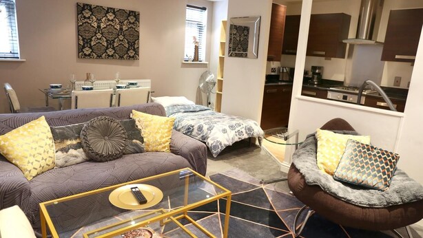 A modern living room with a sofa set, a glass coffee table, and a dining area with a table and chairs. - Home In Birmingham New Street (Birmingham)