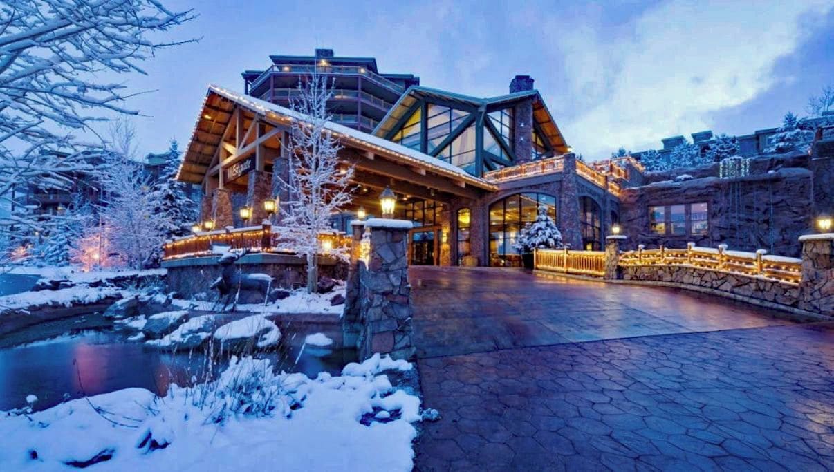 A lodge with a stone facade, a wooden entrance, and a snow-covered landscape.