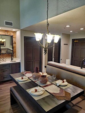 A modern dining area with a long table, benches, and a chandelier.