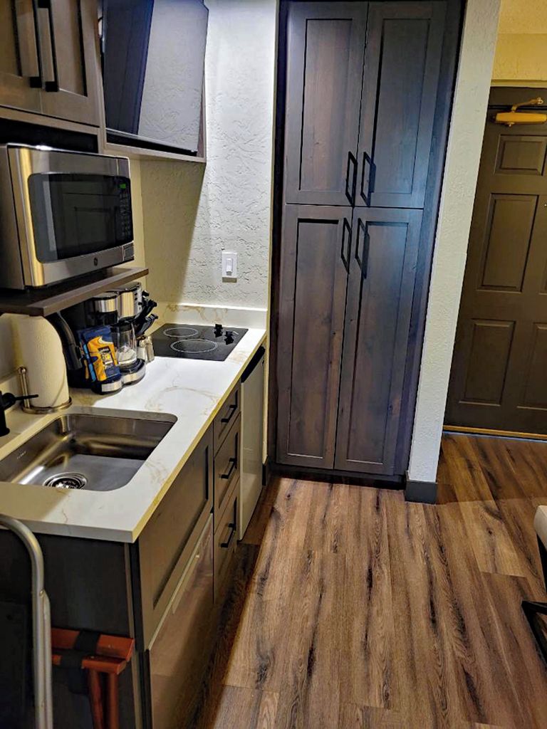 A compact kitchen with a microwave, sink, and cabinets.