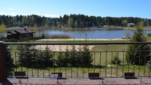 A lakeside view with a balcony, a sandy beach, and a forest in the background. - Laguna House (Garkalnes novads)
