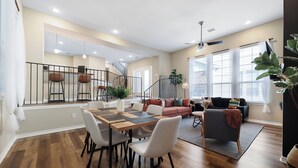A spacious living area with a dining table, chairs, a sofa, and a staircase leading to an upper level. - Tranquil Heights / Stylish Boho Retreat / King Bed / Long term stay (Houston)