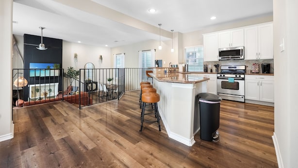 A spacious kitchen with white cabinets, a central island with stools, and a stainless steel oven. - Tranquil Heights / Stylish Boho Retreat / King Bed / Long term stay (Houston)