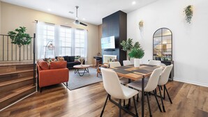 A modern living room with a sofa, coffee table, and dining table with chairs. - Tranquil Heights / Stylish Boho Retreat / King Bed / Long term stay (Houston)