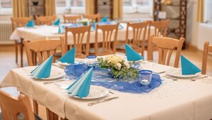 Un espace repas avec des tables dressées pour le repas, agrémenté de serviettes bleues et d’un centre de table composé de fleurs.