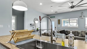 Een moderne keuken met een rvs-spoelbak, een houten afdrukkapel en een plafondventilator.