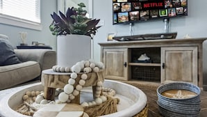 Een gezellige woonkamer met een potplant, een decoratieve houten standaard en een dienblad met stenen en een zeester.