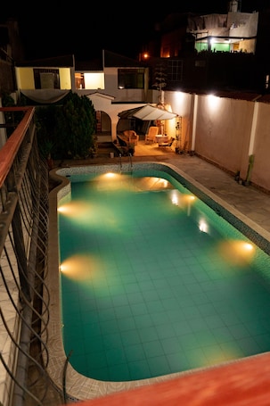 A swimming pool with a tiled deck and a wooden fence.