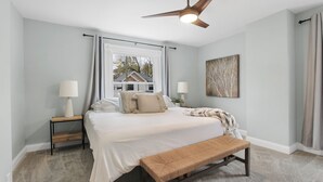A bedroom with a large bed, two bedside tables with lamps, a ceiling fan, a window with curtains, and a wall-mounted artwork. - Stay in the heart of  Oakley (Cincinnati)