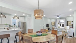 A modern kitchen with white cabinets, a central island, and a dining area with wooden chairs and a round table. - Stay in the heart of  Oakley (Cincinnati)