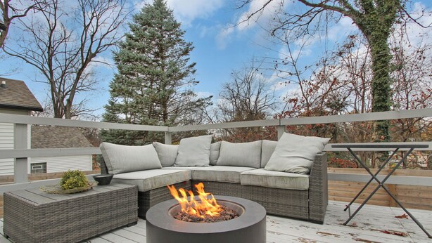 A deck with a fire pit, a gray wicker sofa with cushions, and a small table with a plant. - Stay in the heart of  Oakley (Cincinnati)