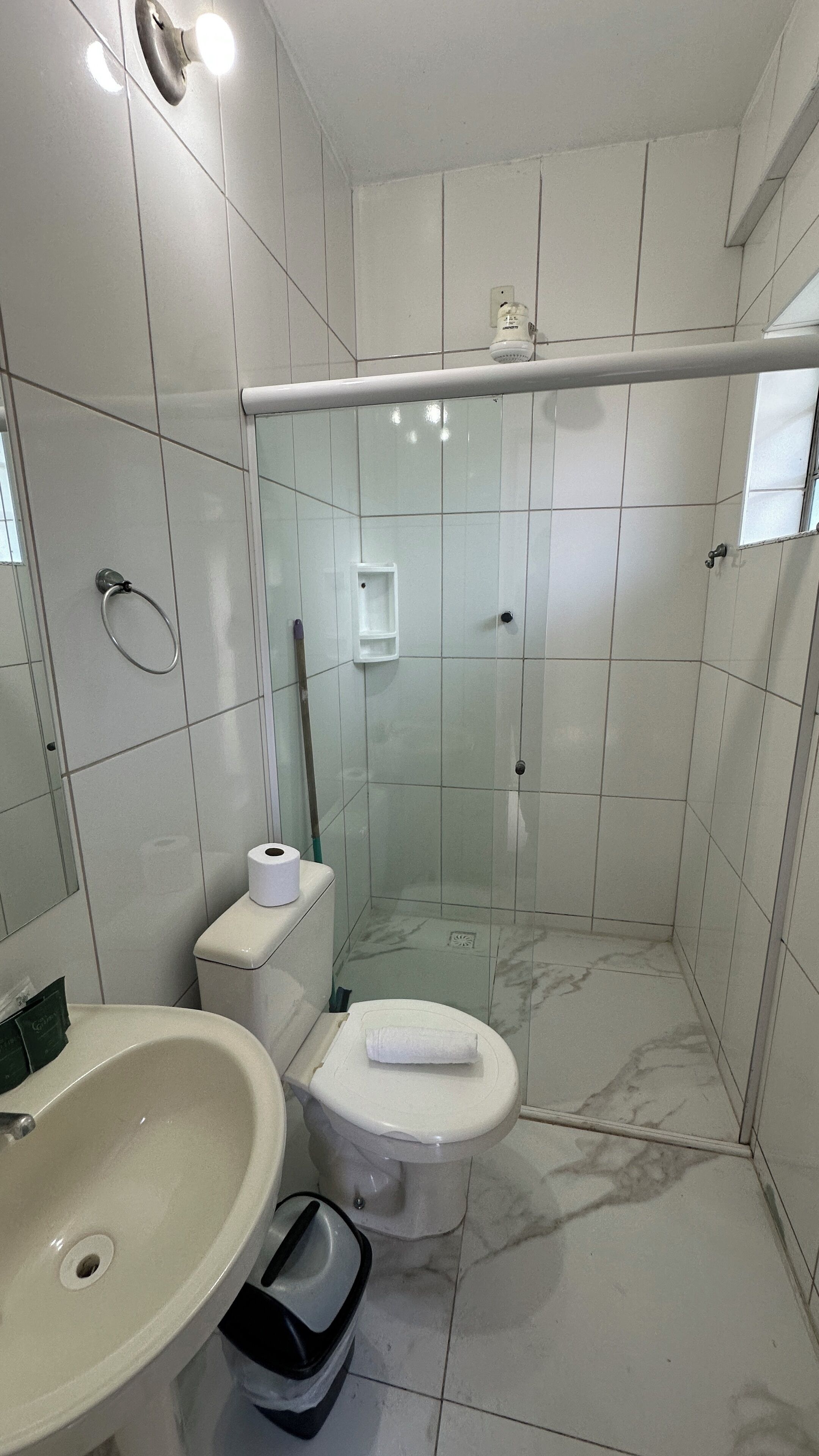 Uma casa de banho moderna com chuveiro, sanita e lavatório.