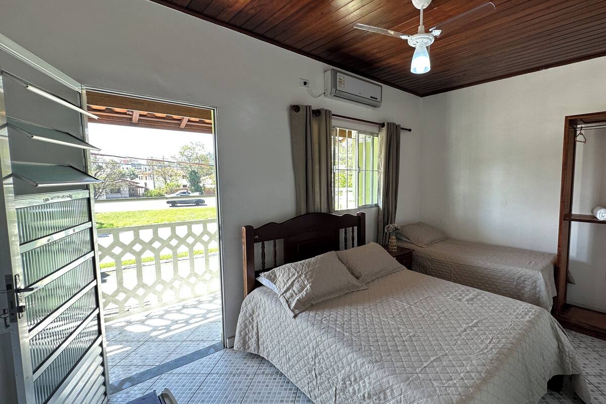 A room with two beds, a ceiling fan, an air conditioning unit, and a view of the outside.