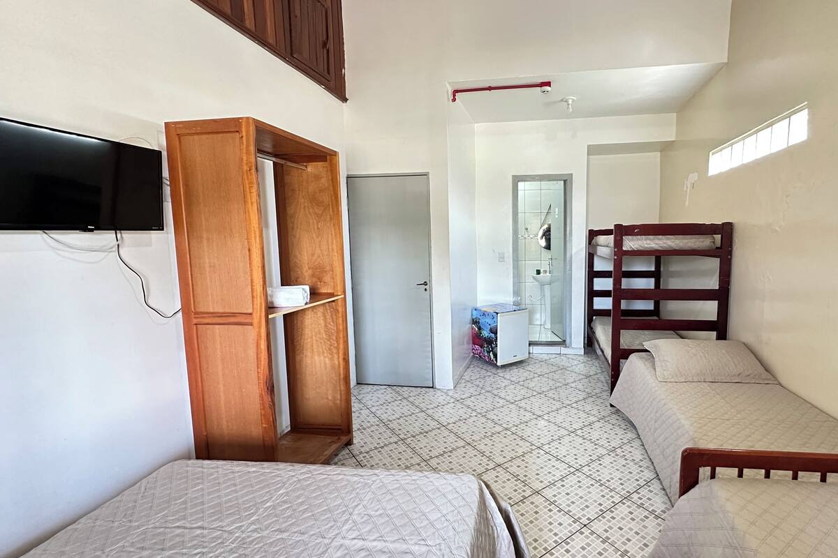 A compact room with bunk beds, a small bathroom, and a TV mounted on the wall.