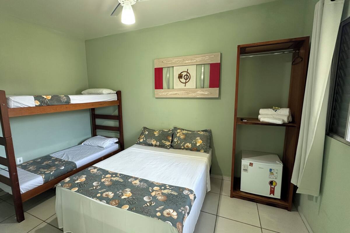 A room with bunk beds, a single bed, a mirror, a small refrigerator, and a wall-mounted artwork.