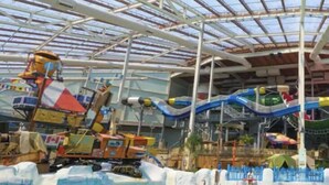 Un parc aquatique intérieur comprenant une piscine, des toboggans et un espace de jeux aquatiques.