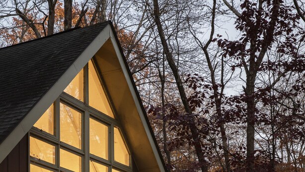 Une maison en bois avec de grandes fenêtres et une terrasse.