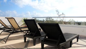 Deux fauteuils confortables sur une terrasse carrelée, offrant une vue sur le paysage urbain.