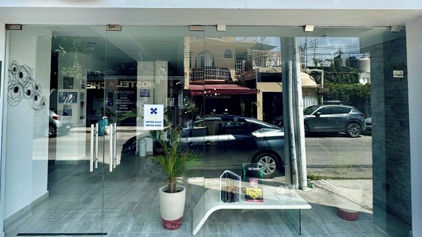 L’entrée de l’hôtel BHF Attraction Hotel Deluxe se distingue par sa façade en verre, son logo représentant un palmier et un panneau indiquant que l’entrée est accessible aux personnes en fauteuil roulant.