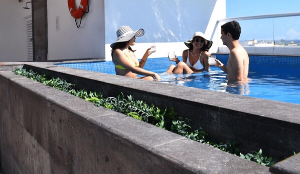 Relax by the pool surrounded by lush greenery and a low stone wall.