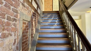 A staircase with wooden steps and a metal handrail, leading to a door with a sign above it. - Wunderschöne Wohnung in Kempten - Stadtmitte (Kempten (Allgäu))