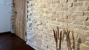 A room with a brick wall, wooden door, and a vase with dried plants. - Wunderschöne Wohnung in Kempten - Stadtmitte (Kempten (Allgäu))