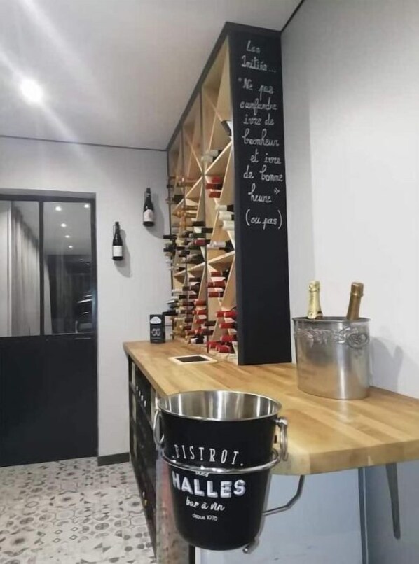 Zona de bar con un menú en pizarra, una estantería para vinos y un cubo con el rótulo 'BISTROT HALLES'.