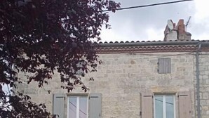 Un bâtiment en pierre doté de deux fenêtres, d’une porte et d’un petit jardin.