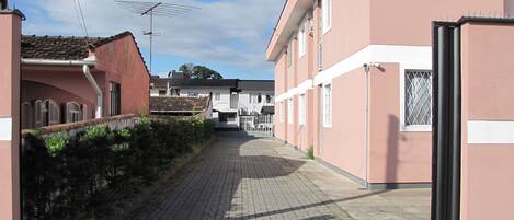 A narrow paved street flanked by buildings with a flat roof and a metal antenna.